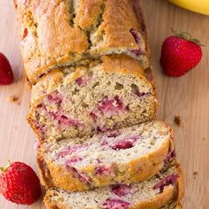 sliced loaf of strawberry banana bread on top of a cutting board with strawberries next to it