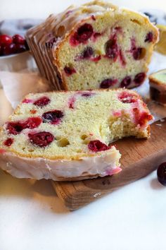 a loaf of cranberry bread sitting on top of a cutting board next to some fruit