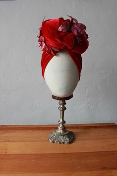 **To Order ** Add some glamour to your work from home look, or stun everyone on your next zoom pub quiz. Feel fabulous in this vintage reproduction headpiece1940's style red velvet turban. This turban is a full covering style knotting at the front with a large knot embellishment in the front.Pink and purple glittered orchids decorate the knotThe turban pulls on, no fastenings or tying knots and it sits snugly and comfortably over the top of the ears.Perfect to keep your hair out of the way whils Valentines Red Velvet, Halloween Headpiece, Star Lily, Rockabilly Accessories, Tying Knots, 1940's Style, Velvet Turban, Pub Quiz, Carmen Miranda