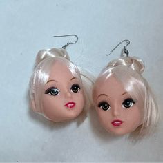 two dolls with blonde hair and blue eyes are sitting side by side on a white surface