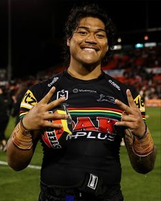 a man with his hands up in the air at a football game, smiling and making peace signs