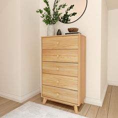 a wooden dresser sitting next to a white rug and a round mirror on the wall