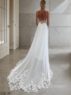 a woman in a white wedding dress looking down at the floor with her back to the camera