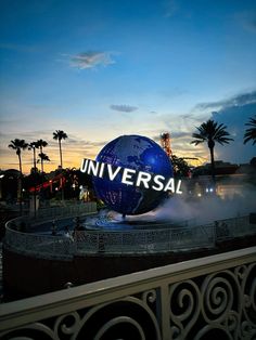 a large blue ball with the word universal on it sitting in front of palm trees