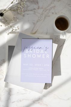 a white table topped with flowers next to a cup of coffee and a paper on top of it