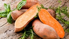 sweet potatoes with leaves and herbs on an old wooden table stock photo ©istoer