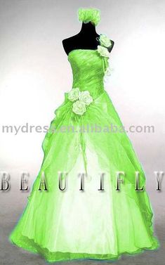 a green wedding dress with flowers on the bustle and skirt is displayed in front of a white background