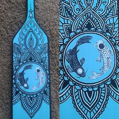 two wooden paddles with designs on them, one blue and the other black in color