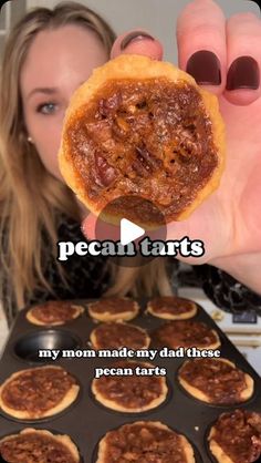 a woman holding up a piece of food in front of a muffin tin with the words pecan tarts on it