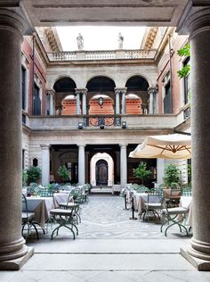 an outdoor dining area with tables and umbrellas on the patio, surrounded by stone pillars