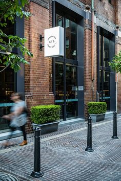 a person is walking down the street in front of a building with black poles and windows