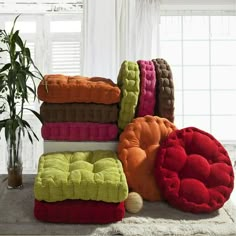 a pile of colorful towels sitting on top of a rug next to a potted plant