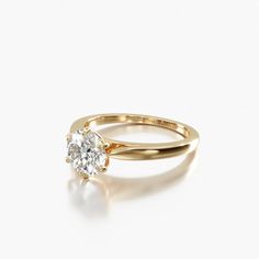 a yellow gold engagement ring with a single diamond in the center, on a white background