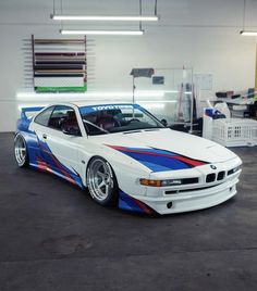 a white car with blue and red stripes parked in a garage