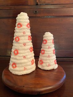 two small white and orange decorated cakes on a wooden table next to an old dresser