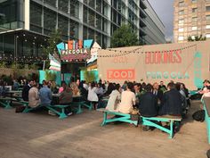 many people are sitting at picnic tables in front of a food truck with a sign on it