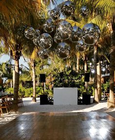 an outdoor party with disco balls hanging from the ceiling and palm trees in the background