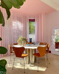 a dining room with pink walls and curtains