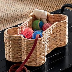 a basket with balls in it sitting on a table next to a handbag and purse