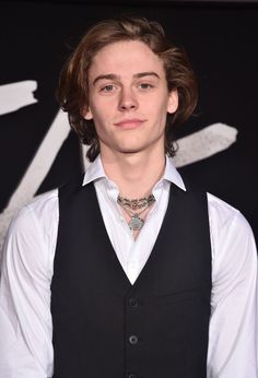 a young man wearing a white shirt and black vest