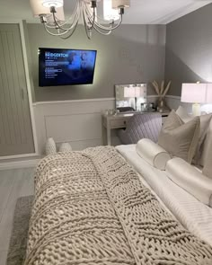 a bedroom with a large bed and a flat screen tv mounted above it's headboard