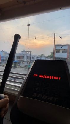 an electronic clock on the back of a bus at sunset or sunrise, in front of a train station