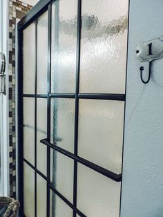 a glass shower door in a bathroom next to a sink and toilet paper dispenser