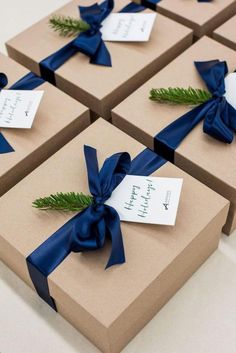 four brown boxes with blue ribbons and tags on them, each wrapped in a bow