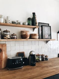 the kitchen counter is covered with bowls, cups and toaster on it's shelf