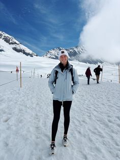 a woman is standing in the snow with her skis on and people behind her