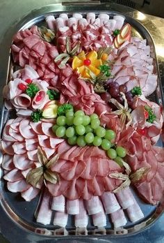 an assortment of meats and grapes on a platter