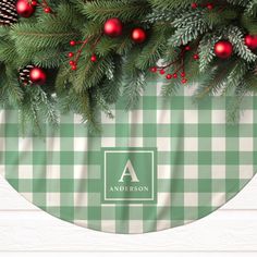 a green and white checkered table cloth with pine cones, red ornaments and evergreen branches