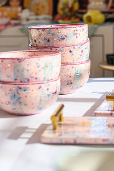 pink and blue cereal bowls sitting on top of a table next to a gold object