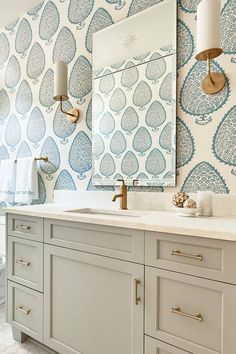 a bathroom with blue and white wallpaper on the walls, two sinks and a large mirror