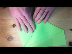 a person cutting up green paper on top of a wooden table