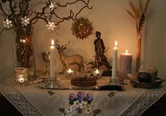 a table topped with candles and deer figurines on top of a lace covered table cloth