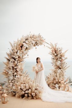 a woman standing in front of a floral arch