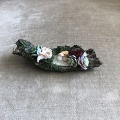 a piece of wood with flowers and shells on it sitting on a carpeted floor