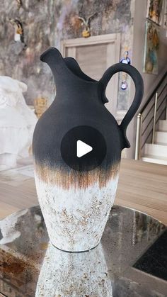 a black and white vase sitting on top of a table next to a stair case