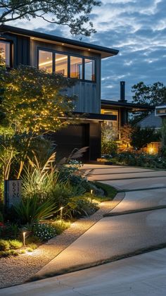 a modern house with lights on the front and side of it at night, lit up by outdoor lighting