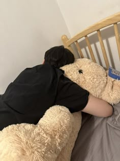 a person laying in bed with a large teddy bear on their back and reading a book