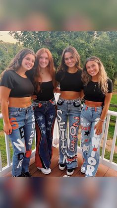 three girls are standing on a porch with their jeans