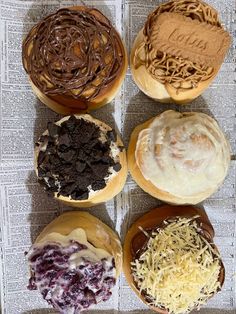 four doughnuts with different toppings are on a newspaper