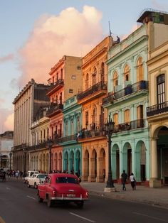 an old car is driving down the street in front of some colorful buildings with balconies and balconies