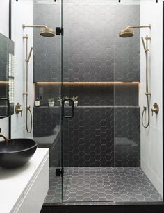 a black and white bathroom with hexagonal tiles on the shower wall, sink and mirror