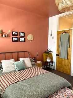 a bed sitting in a bedroom next to a wooden door with pictures on the wall