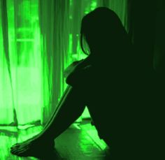 a woman sitting on the floor with her legs crossed in front of a curtained window