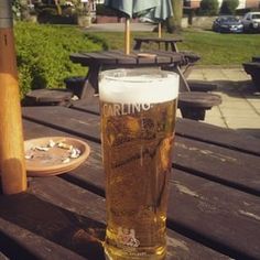 a glass of beer sitting on top of a wooden table next to a baseball bat