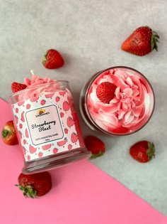 a jar of strawberry butter next to some strawberries on a pink and white surface