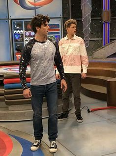 two young men standing in front of a tv set